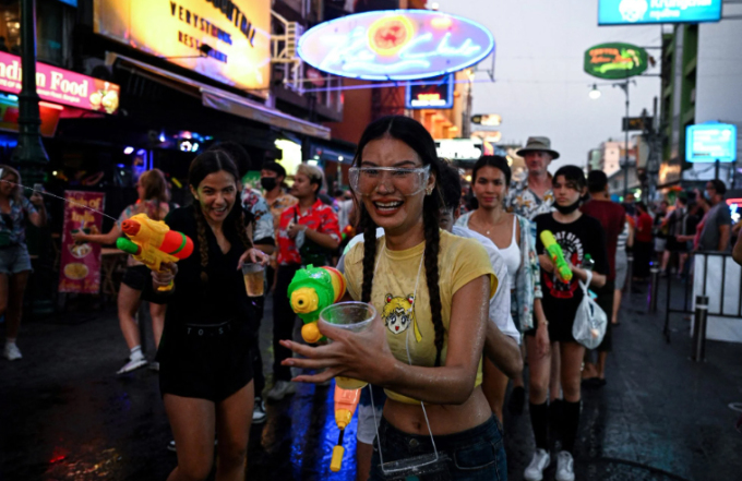 Người trẻ vừa cầm súng nước vừa cầm đồ uống để vui chơi dịp Songkran, Thái Lan. Ảnh: AFP