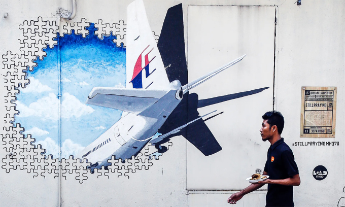 Người Malaysia đi ngang bức tường vẽ tranh tưởng niệm chuyến bay MH370 tại thủ đô Kuala Lumpur tháng 2/2016. Ảnh: AP